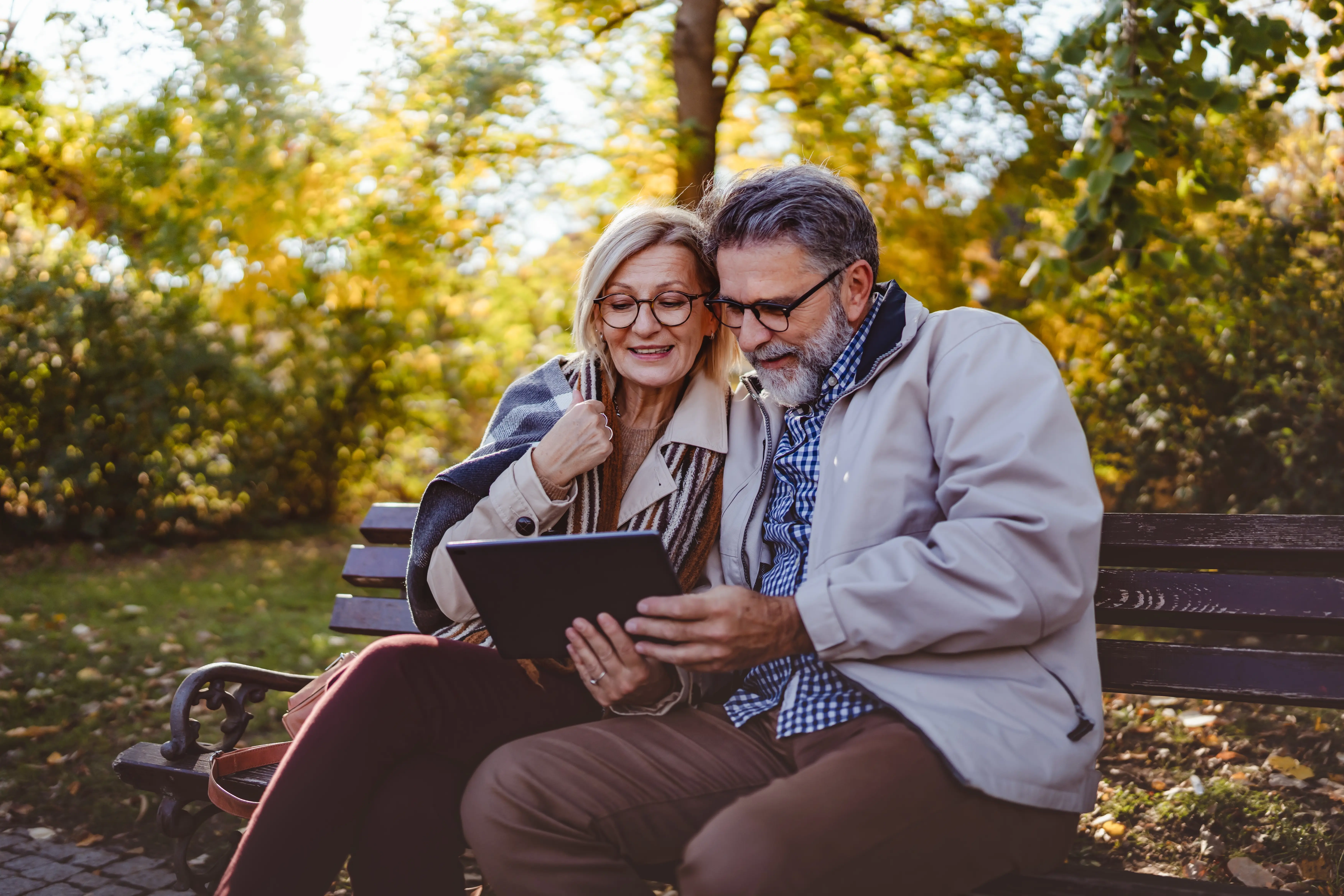 couple senior people happy seated in a bench autumn